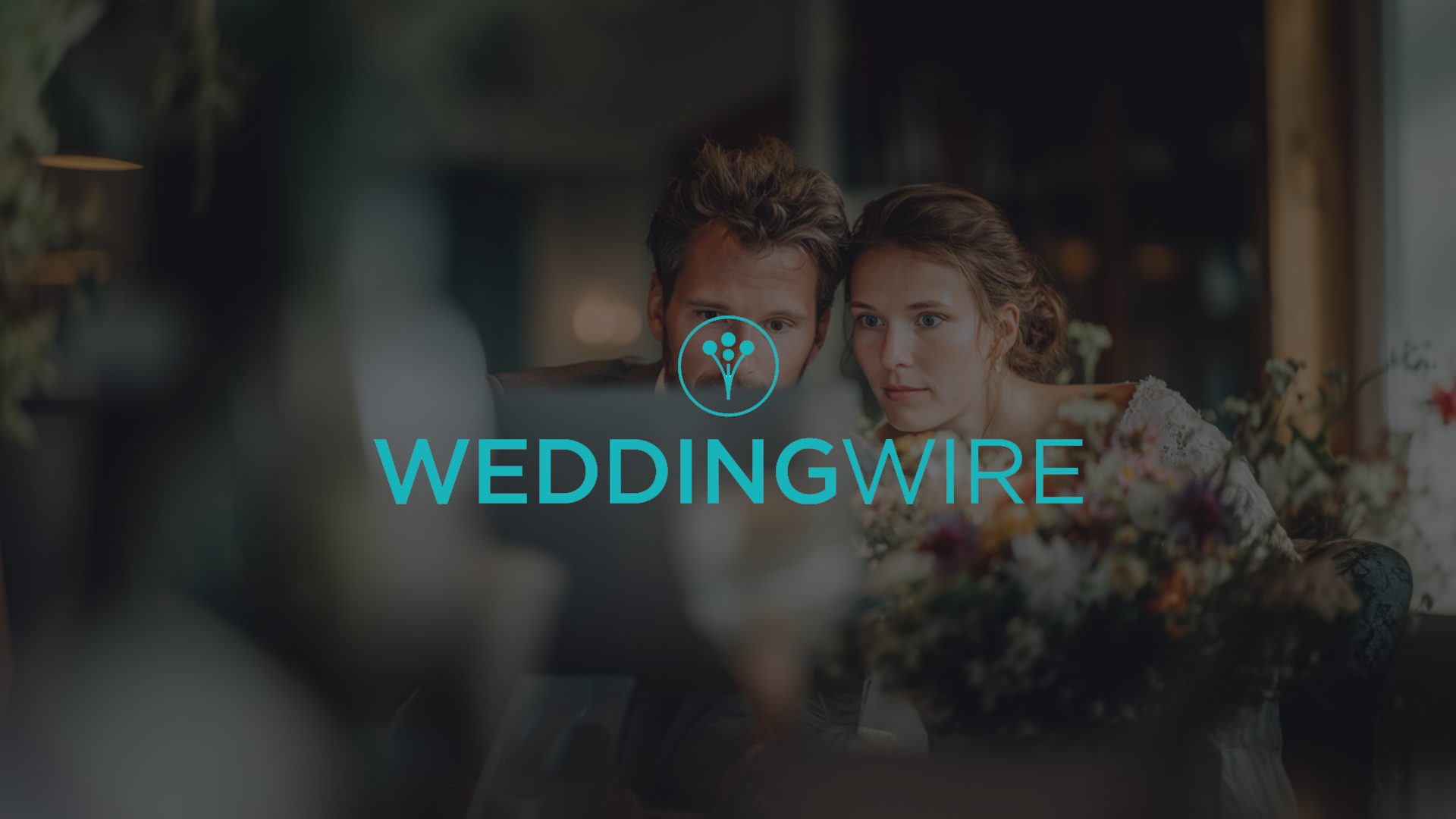 Bruidspaar bekijkt samen een laptop met het WeddingWire-logo