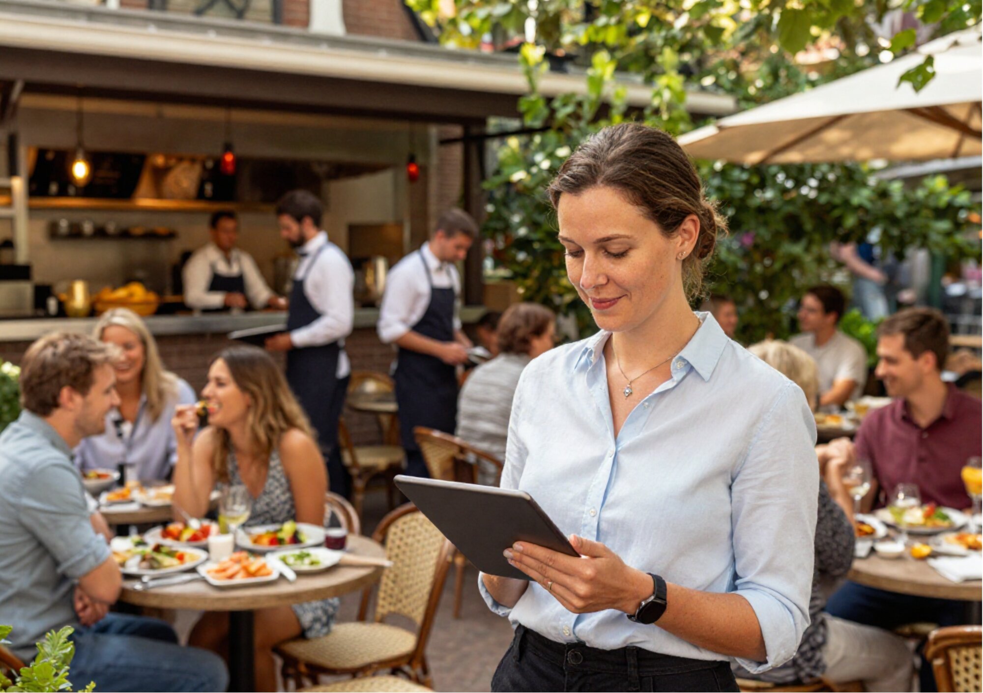 Horecamedewerker bekijkt reserveringen op een tablet op een druk terras